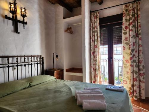 a bedroom with a green bed and a window at Posada La Plaza in Canillas de Albaida