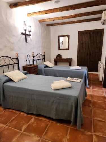 a room with two beds and a cross on the wall at Posada La Plaza in Canillas de Albaida