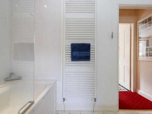 a bathroom with a tub and a shower with a blue towel at Bodkin Cottage in Minehead