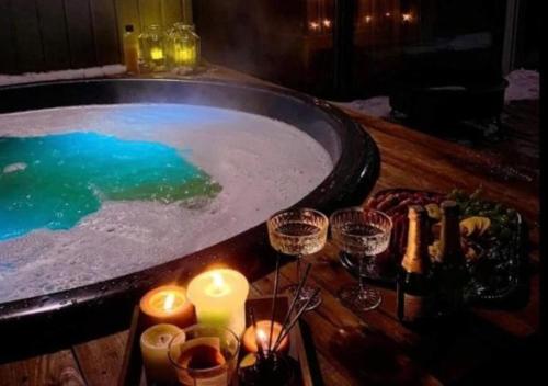 a jacuzzi tub with candles and wine glasses at Cozy Hut with the included Hot Tub-Prime Rentals in Karališkiai