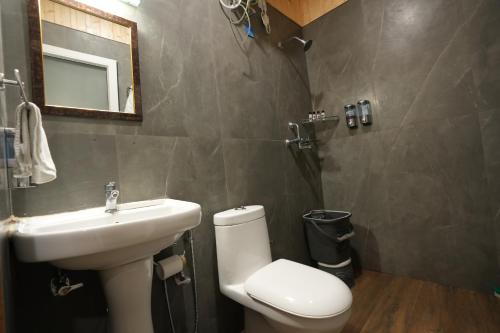 a bathroom with a toilet and a sink and a mirror at THEHIMALAYANLIVING WHISTLING PINES in Mukteswar