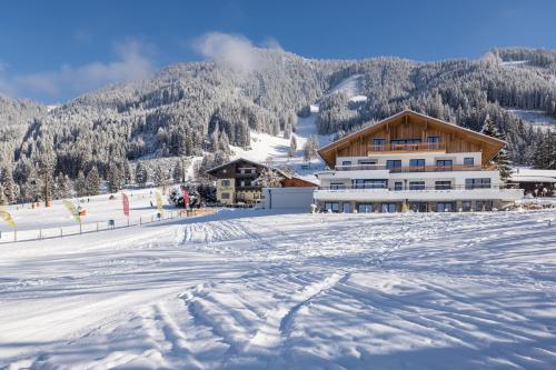 a snow covered ski slope with a lodge in the background at BergLeben Zaglauhof in Werfenweng