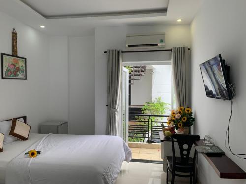 a bedroom with a bed and a desk and a window at Ngọc Sinh Homestay in Hoi An