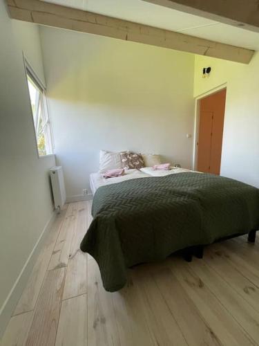 a bedroom with a bed with a green blanket on it at Modern beach house for 12 pers! With jacuzzi in Julianadorp