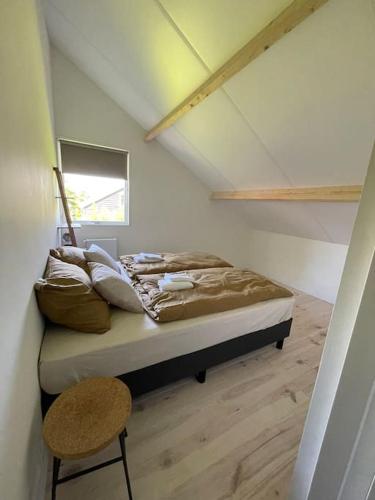 a bedroom with a bed and a chair in a room at Modern beach house for 12 pers! With jacuzzi in Julianadorp