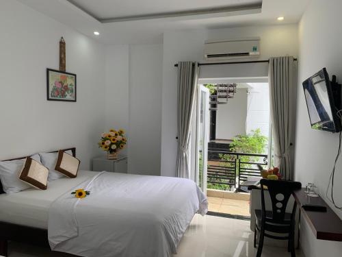 a bedroom with a bed and a desk and a window at Ngọc Sinh Homestay in Hoi An
