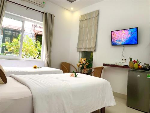 a room with two beds and a tv on the wall at Ngọc Sinh Homestay in Hoi An