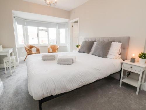 a bedroom with a large white bed with two tables at Tan Y Fron in Penrhyn Bay