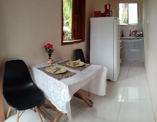 a kitchen with a white table and a white refrigerator at Kitnete Aconchegante in Itacaré