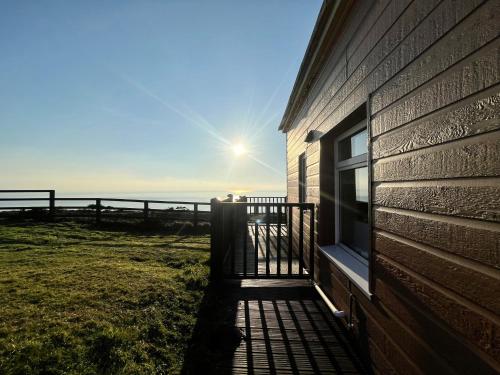 a building with a balcony with the ocean in the background at Sunset sea view chalet with hot tub in Torpoint