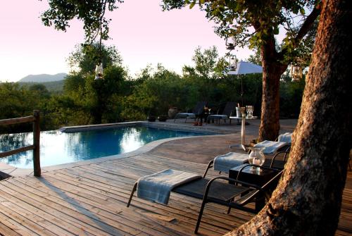 a wooden deck with chairs and a swimming pool at Mbizi Bush Lodge in Grietjie Nature Reserve