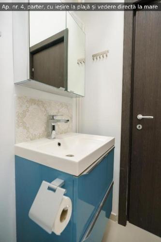 a bathroom with a sink and a toilet paper dispenser at Beach Rooms Roberta in Mamaia