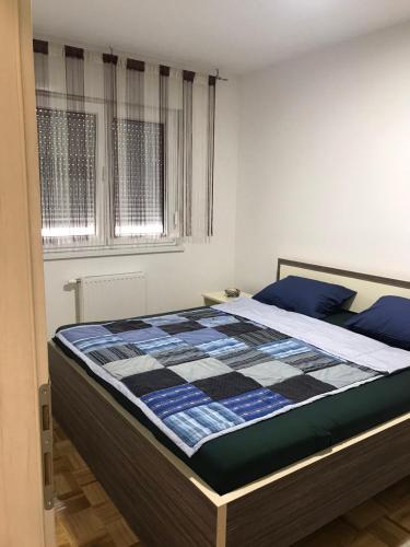 a bedroom with a bed with a checkered blanket on it at Apartman Jaca in Tuzla