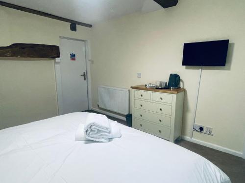 um quarto com uma cama branca e uma televisão em The Royal Oak em Tewkesbury