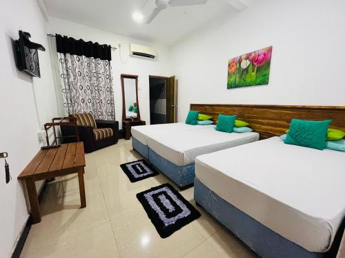 a hotel room with two beds and a table at Tishan Holiday Resort in Polonnaruwa