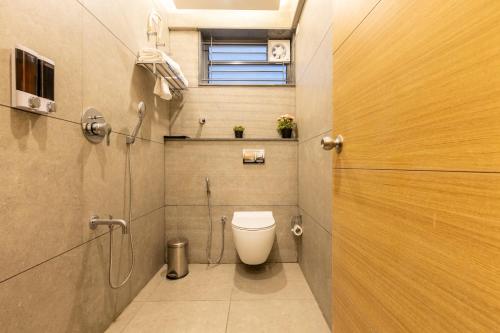 a small bathroom with a toilet and a window at Iris Magnum - APart Hotel in Bengaluru