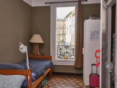 een slaapkamer met een bed, een raam en een koelkast bij vue exceptionnelle sur les canaux in Sète