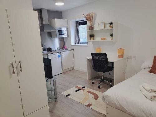 a bedroom with a bed and a desk and a kitchen at Studio apartment within city centre with ensuite in Coventry