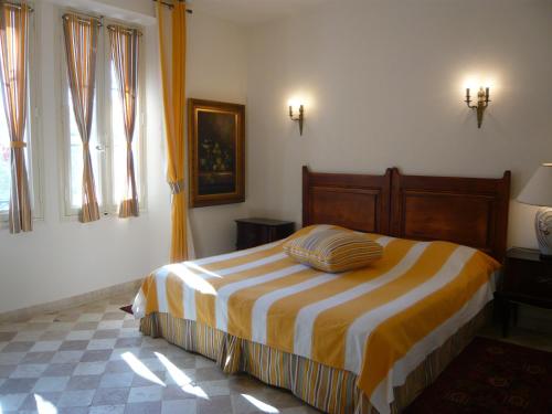 ein Schlafzimmer mit einem Bett mit einer gestreiften Decke in der Unterkunft Auberge de Correns in Correns