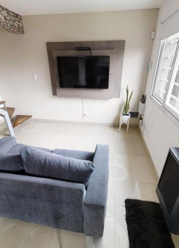 sala de estar con sofá y TV de pantalla plana en HERMOSO DÚPLEX NECOCHEA en Necochea