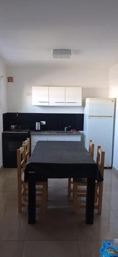 La cuisine est équipée d'une table, de chaises et d'un réfrigérateur. dans l'établissement HERMOSO DÚPLEX NECOCHEA, à Necochea