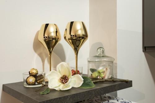 dos jarrones de oro sentados en un estante con flores en Residence Taormina, en Verona