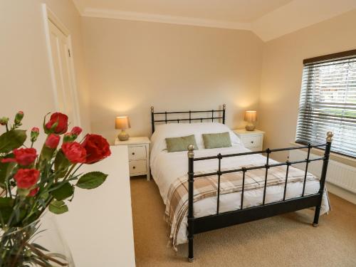 a bedroom with a bed and a vase of red roses at Seagulls Perch in Cowes