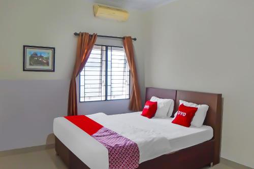 a bedroom with a bed with red pillows and a window at OYO 92314 De Coco Guesthouse in Medan
