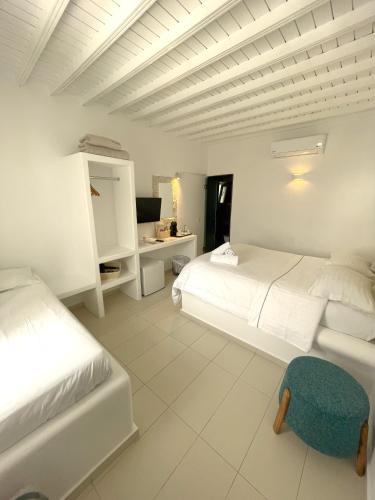 a white bedroom with two beds and a desk at Lefteris in Mýkonos City