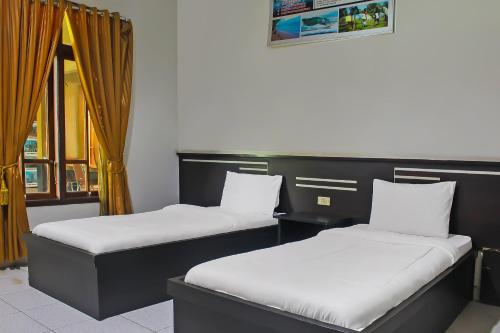 - deux lits assis l'un à côté de l'autre dans une pièce dans l'établissement Collection O 92268 Hotel Aero, à Negarasaka