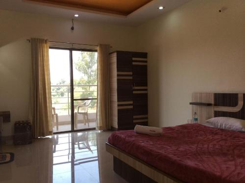 a bedroom with a bed and a sliding glass door at Gugal Residency Mahabaleshwar in Mahabaleshwar