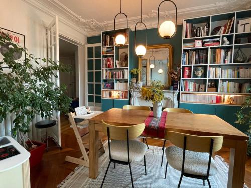 une salle à manger avec une table, des chaises et des étagères dans l'établissement Design Family Appartment in Paris, à Paris