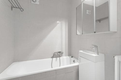 Baño blanco con bañera y lavamanos en Cozy and Quiet 2BR Apartment, en Reikiavik
