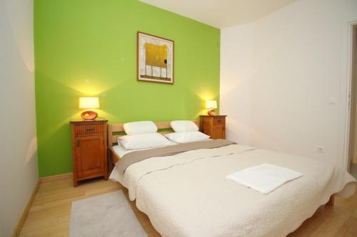 a green bedroom with a bed and two night stands at Apartment Krleza in Baška