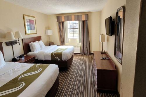 a hotel room with two beds and a flat screen tv at Quality Inn & Suites Columbia I-70 in Columbia