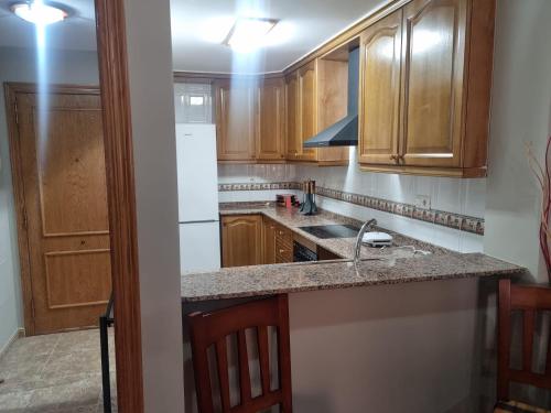 a kitchen with wooden cabinets and a white refrigerator at San Ramón centro Benicarló in Benicarló