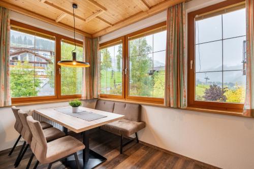a dining room with a table and chairs and windows at Aparthotel Tyrol in Lermoos