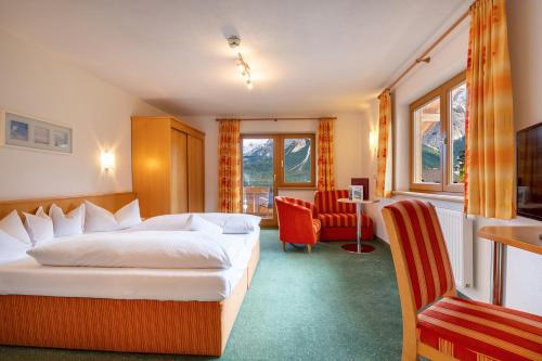 Habitación de hotel con cama y silla en Aparthotel Tyrol en Lermoos