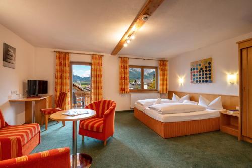 レルモースにあるAparthotel Tyrolのベッド、テーブル、椅子が備わるホテルルームです。