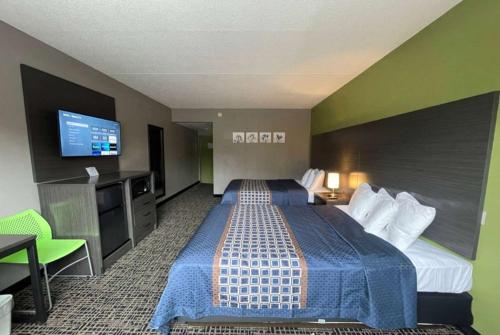 a hotel room with two beds and a flat screen tv at Wingate by Wyndham Lake George in Lake George