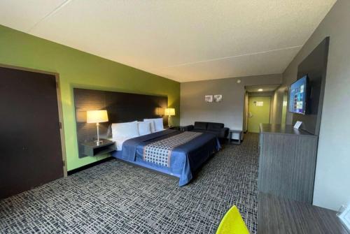a hotel room with a bed and a flat screen tv at Wingate by Wyndham Lake George in Lake George