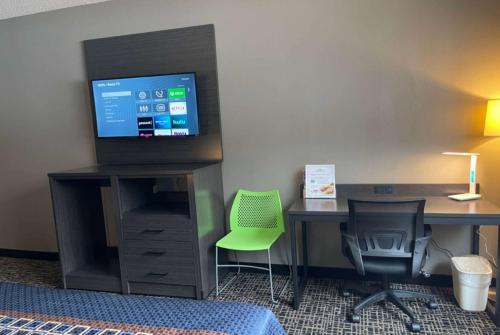 a room with a desk with a computer and a tv at Wingate by Wyndham Lake George in Lake George