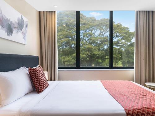 a bedroom with a bed with a large window at BreakFree on Broadway Sydney, an Accor Hotel in Sydney