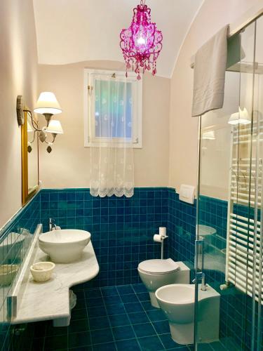 a blue tiled bathroom with two toilets and a chandelier at CERNAIA ROOM in La Spezia