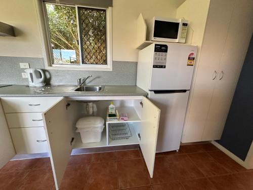 a small kitchen with a white refrigerator and a sink at Mareeba Motor Inn in Mareeba
