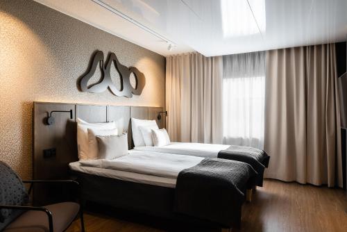 クオピオにあるOriginal Sokos Hotel Puijonsarviのベッド2台と窓が備わるホテルルームです。