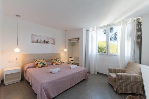 a bedroom with a bed and a chair and a window at Apartamento Ferrera Park 103 in Cala d´Or