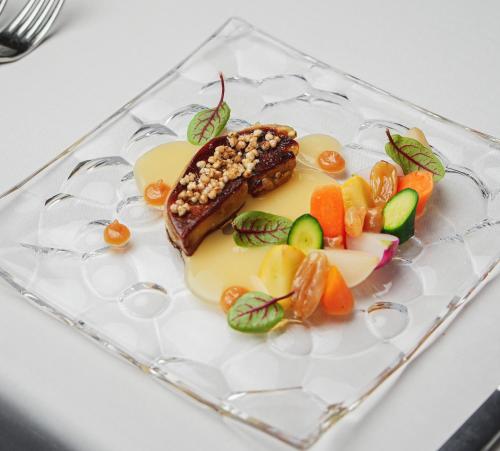a plate of food on a glass plate with fruit at Golden Well in Prague