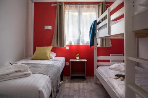 two beds in a room with red walls and a window at Domaine Mélusine - à 2km du Puy duFou France ! in Les Épesses