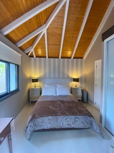 a bedroom with a large bed with two tables and two lamps at Casa de Prazeres in Prazeres